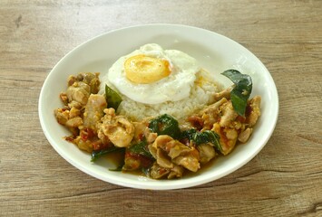 spicy stir fried chicken with mashed dry chili and basil on rice topping egg in plate