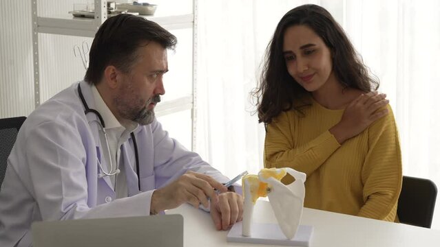 doctor talking to patient with shoulder rotator cuff model consulting and showing medical checkup results at hospital