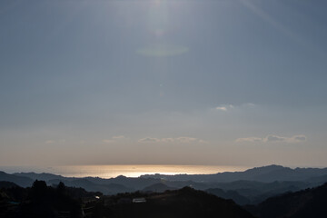 夕日に照らされた海と山