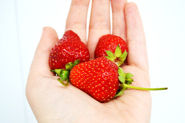 hand is holding a fresh, ripe strawberry. The strawberry is vibrant red in color, with small seeds visible on its surface.  image captures the essence of summer with a delicious strawberry 