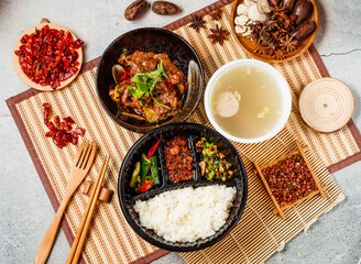 Spicy Boiled beef, white rice, mince meat, soup with coriander, red chilli, chopsticks and fork served in pot isolated on background side view of taiwanese food