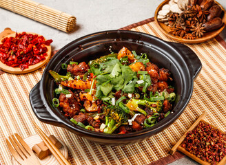 Dry pot spare ribs with red chilli, chopsticks and fork served in pot isolated on background side view of taiwanese food