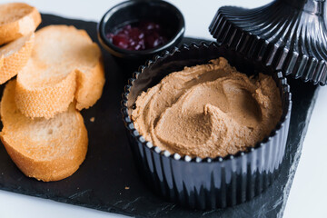 Pate with sauce and croutons on a black board