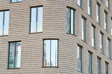 Panoramic glass windows on facade of modern residential building, clinker brick facade, architectural design, innovative use of materials. Clinker brick facade and floor-to-ceiling glass windows
