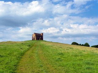 The track up to historic St Catherine’s chapel at Abbotsbury Dorset with green grassy fields and blue skies on a May morning
