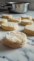 Several biscuits are sitting on a marble counter top with a pot in the background, biscuit dough type