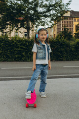 kid girl playing surf skate or skateboard in headphones