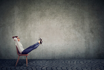 Young businesswoman sitting in office chair with her legs raised up daydreaming 