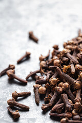 A close-up of dried cloves scattered on a textured gray surface, Indian Indonesian spice