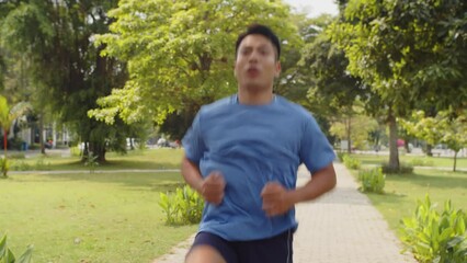 Tilt up shot of motivated Asian male athlete doing jumping exercise when warming up in park