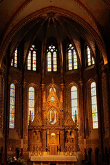 Fototapeta premium Elaborate altar in front of stained glass windows in gothic style shape inside the Matthias Church, Budapest, Hungary