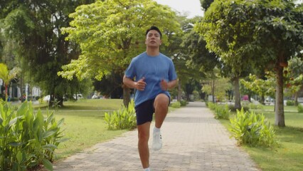 Long shot of active Asian man jumping while working out in local city park alone