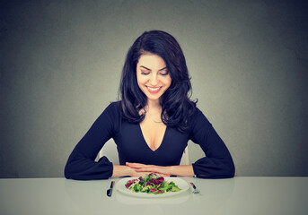 Happy woman sitting at table with a salad plate ready for a detox diet plan 