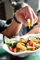 Close-up of a hand squeezing fresh lime over a vibrant plate of food, emphasizing the importance of fresh ingredients in cuisine