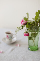 Moody summer still life. Table composition with cup of coffee, tea and beautiful floral bouquet with pink roses