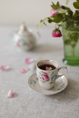 Moody summer still life. Table composition with cup of coffee, tea and beautiful floral bouquet with pink roses