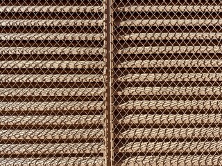 Metal vent peeks from behind a chain link fence, merging industrial functionality with a hint of...