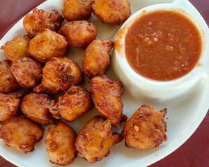 Fried vegetable fritters and a dip in a plate, Indian snacks photography, street food background 