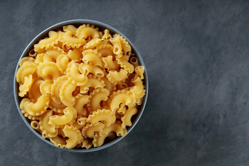 Raw Creste di Gallo Pasta in Ceramic Bowl on Dark Concrete Background, Copy Space