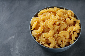 Raw Creste di Gallo Pasta in Ceramic Bowl on Dark Concrete Background, Copy Space