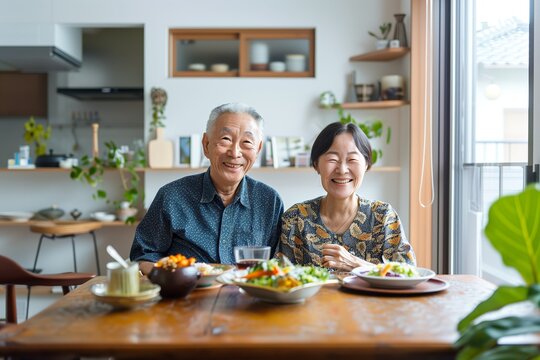 Portrait of a senior japanese couple happily enjoying a meal together at home, white clean modern living room