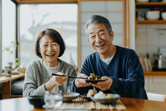 A senior japanese couple happily enjoying a meal together at home, white clean modern living room