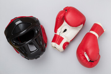 Boxing helmet and gloves on color background, top view.