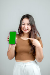 Studio portrait of a beautiful young Asian Indonesian woman holding or playing a smart phone