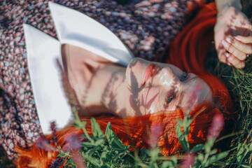 red-haired woman lies peacefully on the ground, surrounded by vibrant flowers in a lush field in Ukraine, exuding serenity and natural beauty amidst a colorful, blooming landscape