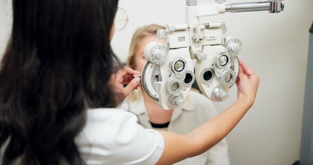 Doctor, optometry and woman on phoropter for eye care, consultation or health exam in clinic. Ophthalmologist, test or patient on lens machine tool for vision check, wellness and eyesight correction