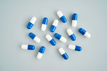 A lot of white and blue pills on a blue background.