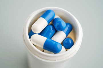 Blue and white capsules in a jar close-up.