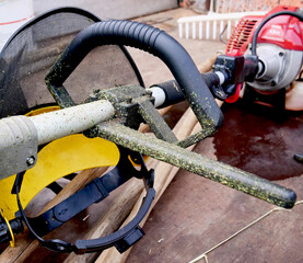 Handle of a brush cutter with a petrol engine and signs of cut grass