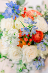 A beautiful bridal bouquet with white roses, blue flowers, and reds