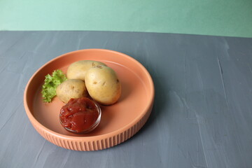 Raw potatoes and tomato sauce on a plate on a gray background. Vegetarianism and raw food