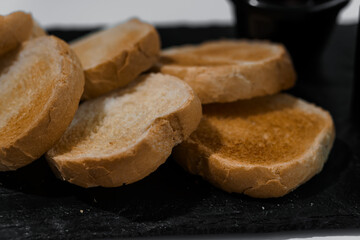 Pate with sauce and croutons on a black board on a white background