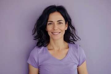 Fototapeta premium Portrait of a smiling woman with straight dark hair, wearing a casual gray shirt against a gray background
