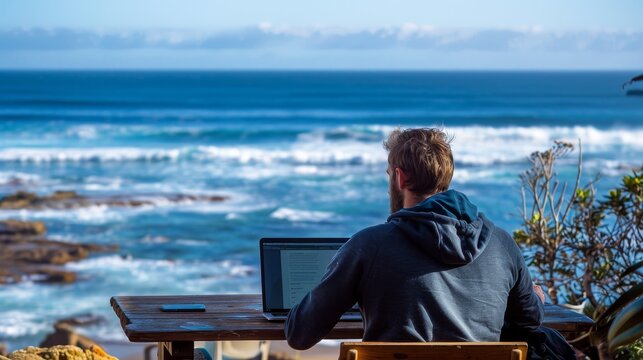 Man working on laptop with beach view, blending remote work and travel. Perfect scene for digital nomads and freelancers seeking inspiration.