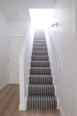 Minimalist, white painted hallway and staircase of a converted Edwardian house in north London....