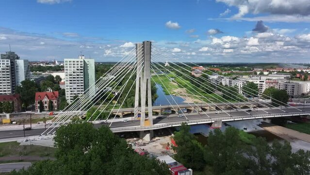 Flight towards the pylons of the Emperor Otto Bridge in Magdeburg. Sunny weather, cloudy sky. Apartment blocks and Zollelbe in the background, cars driving on the bridge.
