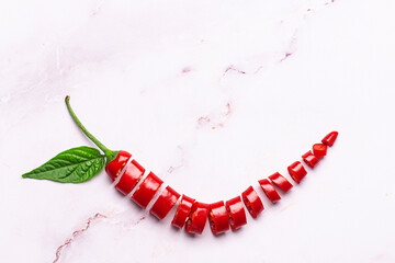 Sliced red Chili pepper on light marble background with copy space for your design.