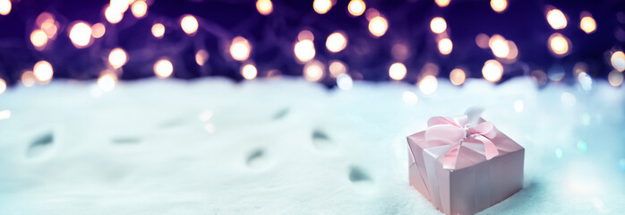 Silk box on a winter background with twinkling lights, foot prints in the snow
