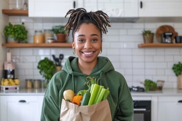 asian couple in green hoodies with paper bag full of vegetables standing in minimal kitchen smiling after grocery shopping at eco market, 0km food concept