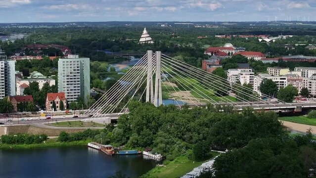 Flight next to the Emperor Otto Bridge in Magdeburg. Sunny weather, cloudy sky. Apartment blocks, "Zollelbe" and "Bugaturm" in the background, cars driving on the bridge. Wide view into the distance.