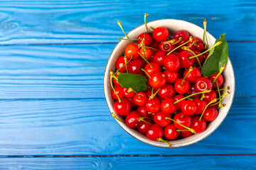 Cherries. Fresh ripe cherries with leaves on a textured wooden background. Fresh sweet organic cherry pile. Berries and fruits. Vegan. Healthy eating. Place for text. Copy space