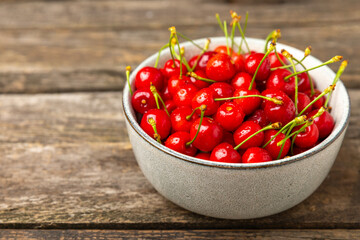 Cherries. Fresh ripe cherries with leaves on a textured wooden background. Fresh sweet organic cherry pile. Berries and fruits. Vegan. Healthy eating. Place for text. Copy space