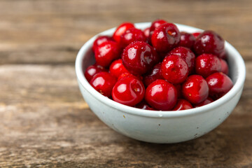 Cherries. Fresh ripe cherries with leaves on a textured wooden background. Fresh sweet organic cherry pile. Berries and fruits. Vegan. Healthy eating. Place for text. Copy space