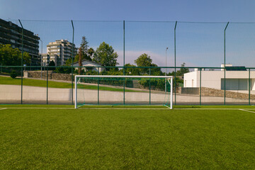 Sports field in a residential area with artificial green grass and football goal at Santo Tirso Municipal Sports Complex in Portugal.