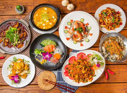 Chongqing Boiled Fish, Crab Roe and Tofu Pot, Pineapple Shrimp Balls, Comprehensive sashim, seafood salad, Kung Pao Chicken, Soft Shell Crab, Bean crispy fresh oysters with chopsticks side view