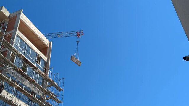 A crane lifting metal structures at a great height for the construction of a multi-story building. Construction industry.